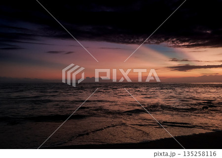 Ocean at Sunset with Dramatic Sky, Rippling Water, and Cloud Formations Reflecting Natural Light for Serene Coastal Scenery 135258116