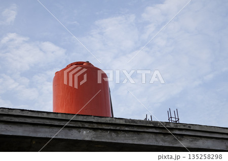 Orange Water Tank on Roof with Cloudy Sky in Background for Water Storage and Supply System under Natural Light Orange Water Tank on Roof with Cloudy Sky in Background for Water Storage and Supply System under Natural Light 135258298