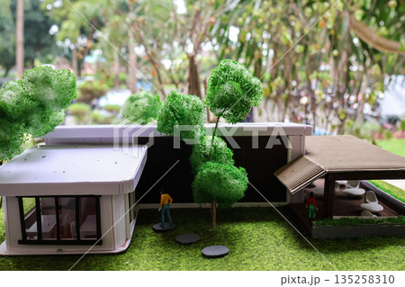 Architectural model showcasing modern house design with miniature figures and landscaping under natural light, ideal for real estate visualization Architectural model showcasing modern house design with miniature figures and landscaping under natural light, ideal for real estate visualization 135258310