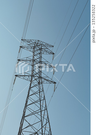 High voltage electricity pylon under clear blue sky transmitting power with overhead lines and lattice structure against copy space in natural light for infrastructure needs High voltage electricity pylon under clear blue sky transmitting power with overhead lines and lattice structure against copy space in natural light for infrastructure needs 135258322