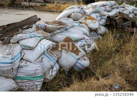 Pile of damaged sandbags with grain spillage, creating a textured foreground, perfect for construction or environmental themed presentations 135258340