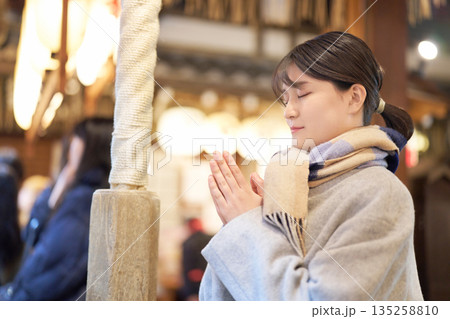 夜の神社で願い事をする若い女性 135258810