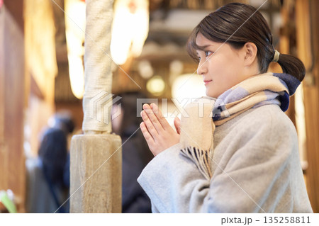 初詣で真剣に願い事をするマフラー姿の女性 初詣で真剣に願い事をするマフラー姿の女性 135258811