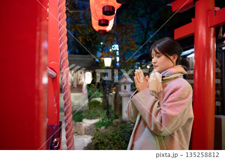 初詣で真剣に願い事をするマフラー姿の女性 135258812