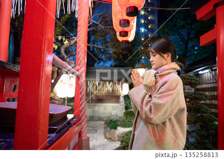 夜の神社で祈願をする若い女性 135258813