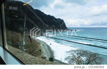 山陰本線の鈍行列車に乗って冬の日本海を眺めているイメージ風景 135260302