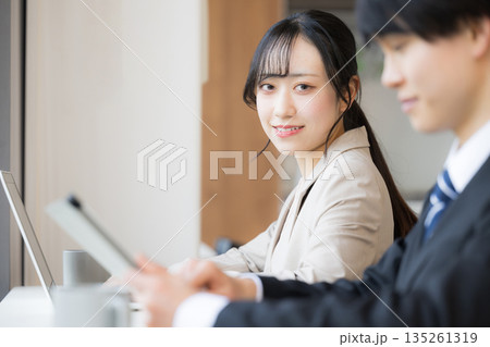 落ち着いたオシャレなカフェやオフィス空間で、ノートパソコンを使う若い女性のカメラ目線の笑顔 落ち着いたオシャレなカフェやオフィス空間で、ノートパソコンを使う若い女性のカメラ目線の笑顔 135261319