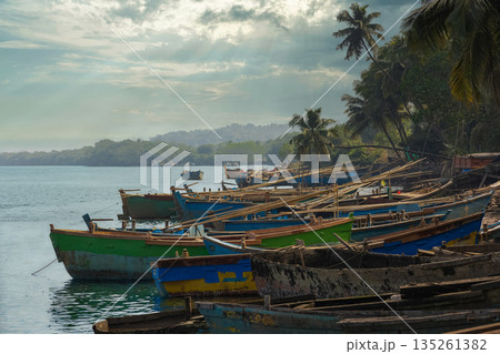 Wooden boats anchored by the river with dramatic sky background. Wooden boats anchored by the river with dramatic sky background. 135261382