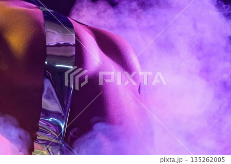 Woman posing with reflective clothing in purple smoke during nighttime in studio 135262005