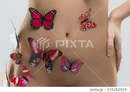 Butterflies placed on a person's stomach during a creative body art session in a studio setting Butterflies placed on a person's stomach during a creative body art session in a studio setting 135262029