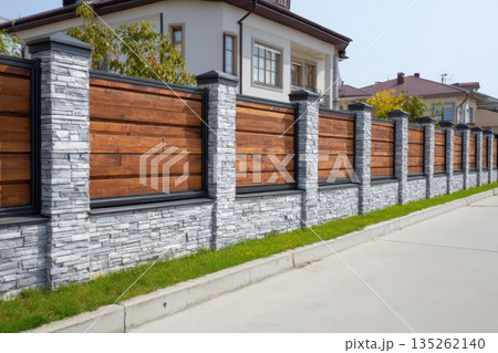 Nice brown wooden fence around house. Garden vinyl fence built with a gray concrete pillar columns surrounding yard. Outdoor landscape. Security and privacy concept. Residential neighborhood. 135262140
