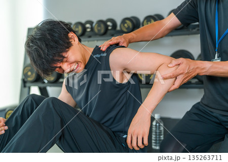 肩関節を痛がるトレーニングをする男性とスポーツ理学療法士の男性スタッフ 135263711