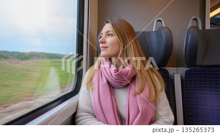 serene woman observing passing scenery, calm lady admiring scenic countryside from train window 135265373