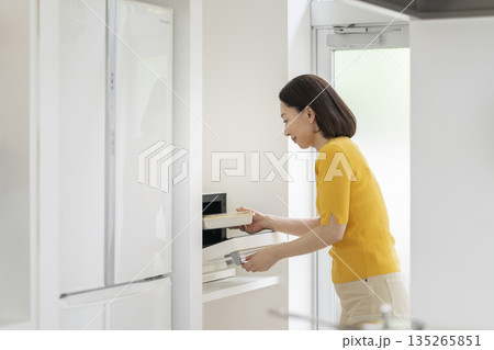 電子レンジでお弁当を温める50代の女性 電子レンジでお弁当を温める50代の女性 135265851
