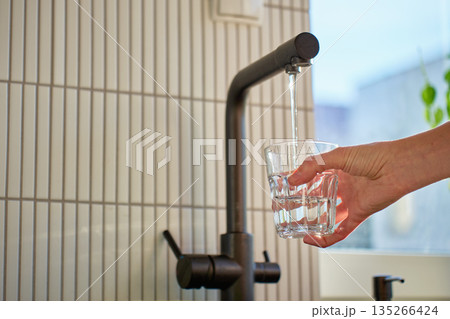 Hand filling glass with drinking water from kitchen faucet Hand filling glass with drinking water from kitchen faucet 135266424