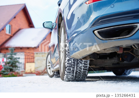Car with winter tires parked on snowy road near house 135266431