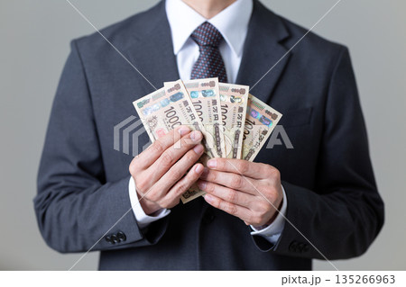お金を持つスーツ姿のミドル男性ビジネスマン 135266963