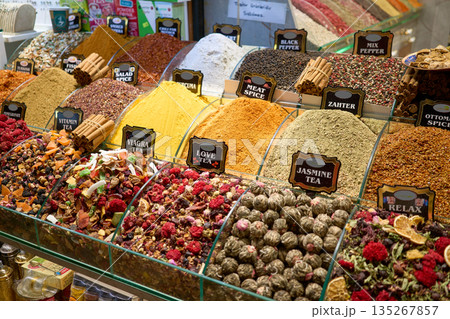 A vibrant display of various spices and teas, including black pepper, turmeric, and jasmine tea, at a bustling market stall. A vibrant display of various spices and teas, including black pepper, turmeric, and jasmine tea, at a bustling market stall. 135267857