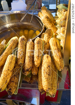 A close-up shot showcases grilled corn on the cob at a street food vendor, perfect for a summer treat. 135267867