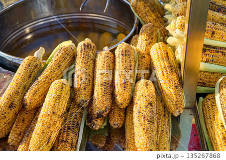 Close-up of grilled corn on the cob, a popular street food snack, ready to eat. The golden-brown kernels are delicious. 135267868