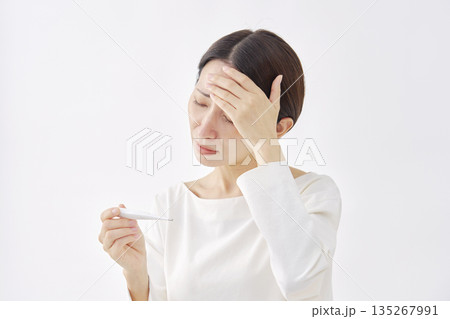 体温計で体温を測る女性　白背景 135267991