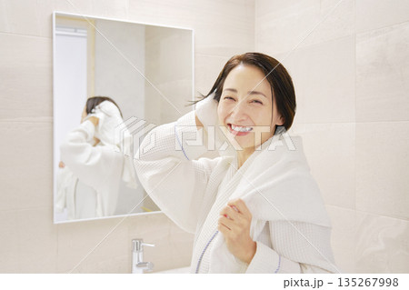 お風呂上がりに濡れている髪をバスタオルで拭く女性　カメラ目線　ポートレート 135267998