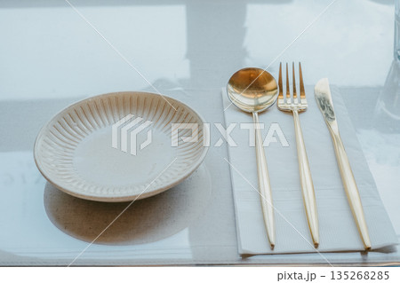 Modern Table Setting with Gold Cutlery and Ceramic Plate 135268285