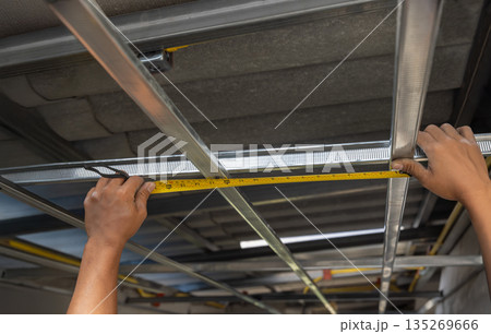 Worker is installing metal profiles for gypsum board ceiling in renovate house. Worker is installing metal profiles for gypsum board ceiling in renovate house. 135269666