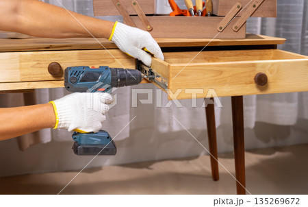 Handyman repair wooden drawer of cabinet in living room. 135269672