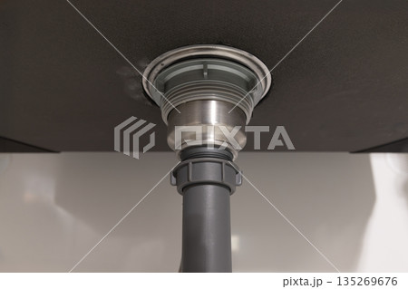 Plumber fixing drain clog under sink. 135269676