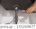 Plumber fixing drain clog under sink. 135269677