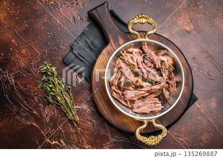 Close-up of succulent pulled brisket piled high on a rustic wooden board, garnished with fresh herbs, delicious meal. brown background. top view Close-up of succulent pulled brisket piled high on a rustic wooden board, garnished with fresh herbs, delicious meal. brown background. top view 135269887