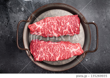 Premium denver, chuck eye steak, beautifully presented, ready for seasoning. A versatile cut ideal for barbecue enthusiasts and steak lovers alike. black background. top view 135269935
