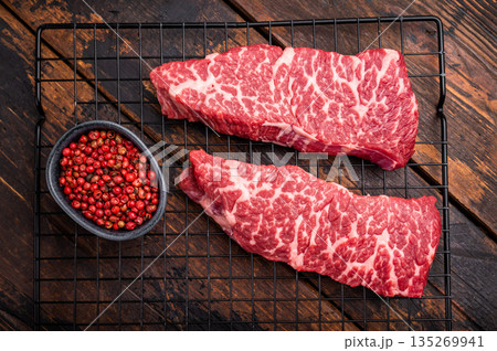 Beef shoulder tender, raw denver steak waiting to be transformed into a gourmet dish. Ideal for grilling or roasting for an unforgettable dinner. wooden background. top view 135269941