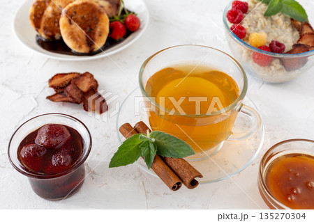 Glass cup of green tea with cinnamon and leaves of mint on a saucer. Glass cup of green tea with cinnamon and leaves of mint on a saucer. 135270304