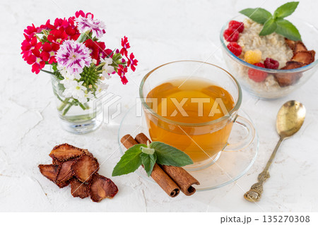 Glass cup of green tea with cinnamon and leaves of mint on a saucer. Glass cup of green tea with cinnamon and leaves of mint on a saucer. 135270308