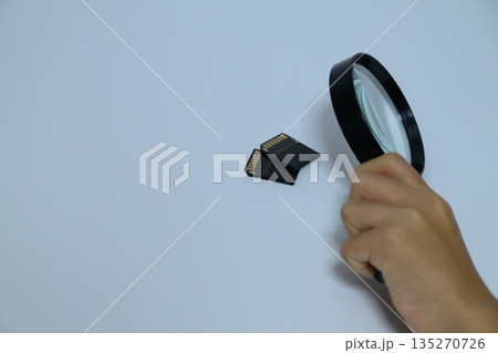 虫眼鏡でSDカードをチェックする横位置写真 135270726