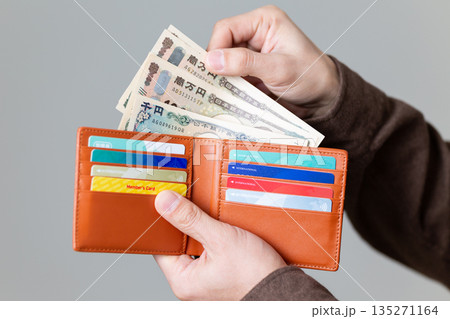 財布からお金を出すカジュアル姿のミドル男性ビジネスマン 財布からお金を出すカジュアル姿のミドル男性ビジネスマン 135271164