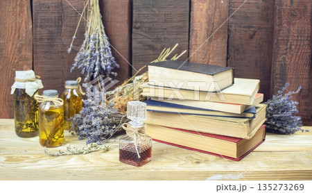 Healing herbal remedies, ancient books, bouquets of mystical herbal potions and candles on wooden background Healing herbal remedies, ancient books, bouquets of mystical herbal potions and candles on wooden background 135273269
