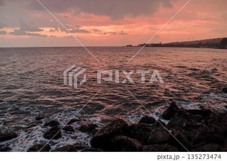 Sunset Over Ocean Waves Crashing on Rocks with Orange Sky and Copy Space, conveying tranquility and perfect for travel and vacation ads Sunset Over Ocean Waves Crashing on Rocks with Orange Sky and Copy Space, conveying tranquility and perfect for travel and vacation ads 135273474