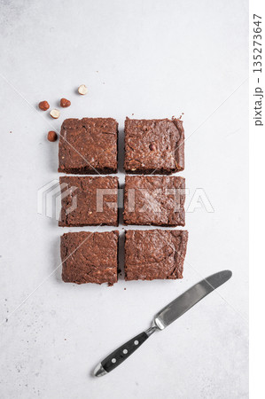Pieces of chocolate brownie on a light background with nuts and knife. Pieces of chocolate brownie on a light background with nuts and knife. 135273647