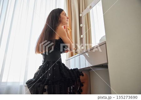 Woman applying face powder with a brush, getting ready for an event Woman applying face powder with a brush, getting ready for an event 135273690
