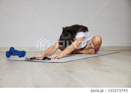 Woman performing a child's pose on a yoga mat during a home workout for wellness Woman performing a child's pose on a yoga mat during a home workout for wellness 135273743