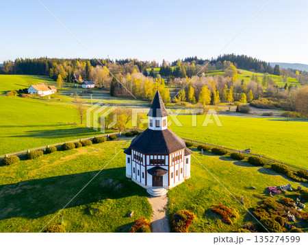 The Tesarov Chapel stands majestically in Korenov, surrounded by lush greenery and mountains. This aerial view showcases its unique architecture and picturesque landscape, highlighting its charm. The Tesarov Chapel stands majestically in Korenov, surrounded by lush greenery and mountains. This aerial view showcases its unique architecture and picturesque landscape, highlighting its charm. 135274599