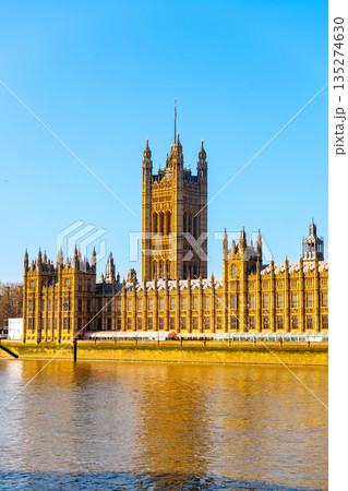 The Palace of Westminster stands majestically against a clear blue sky, its towers glistening in the sunlight over the calm waters of the River Thames, showcasing London historic architecture. The Palace of Westminster stands majestically against a clear blue sky, its towers glistening in the sunlight over the calm waters of the River Thames, showcasing London historic architecture. 135274630