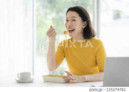 デスクワークでランチを食べる50代の女性　イメージ 135274761