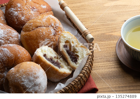 木のテーブルの上のトレーに並んでいるあんドーナツと緑茶 135274889