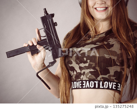 Woman wearing headphones holding gun Woman wearing headphones holding gun 135275248