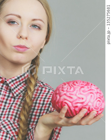 Woman thinking and holding fake brain Woman thinking and holding fake brain 135275681