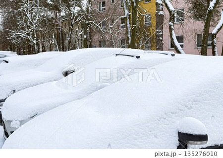 Parked cars sit completely covered in thick layer of fresh snow in residential area. Extreme weather events, buried cars, winter maintenance, seasonal challenges. Parked cars sit completely covered in thick layer of fresh snow in residential area. Extreme weather events, buried cars, winter maintenance, seasonal challenges. 135276010